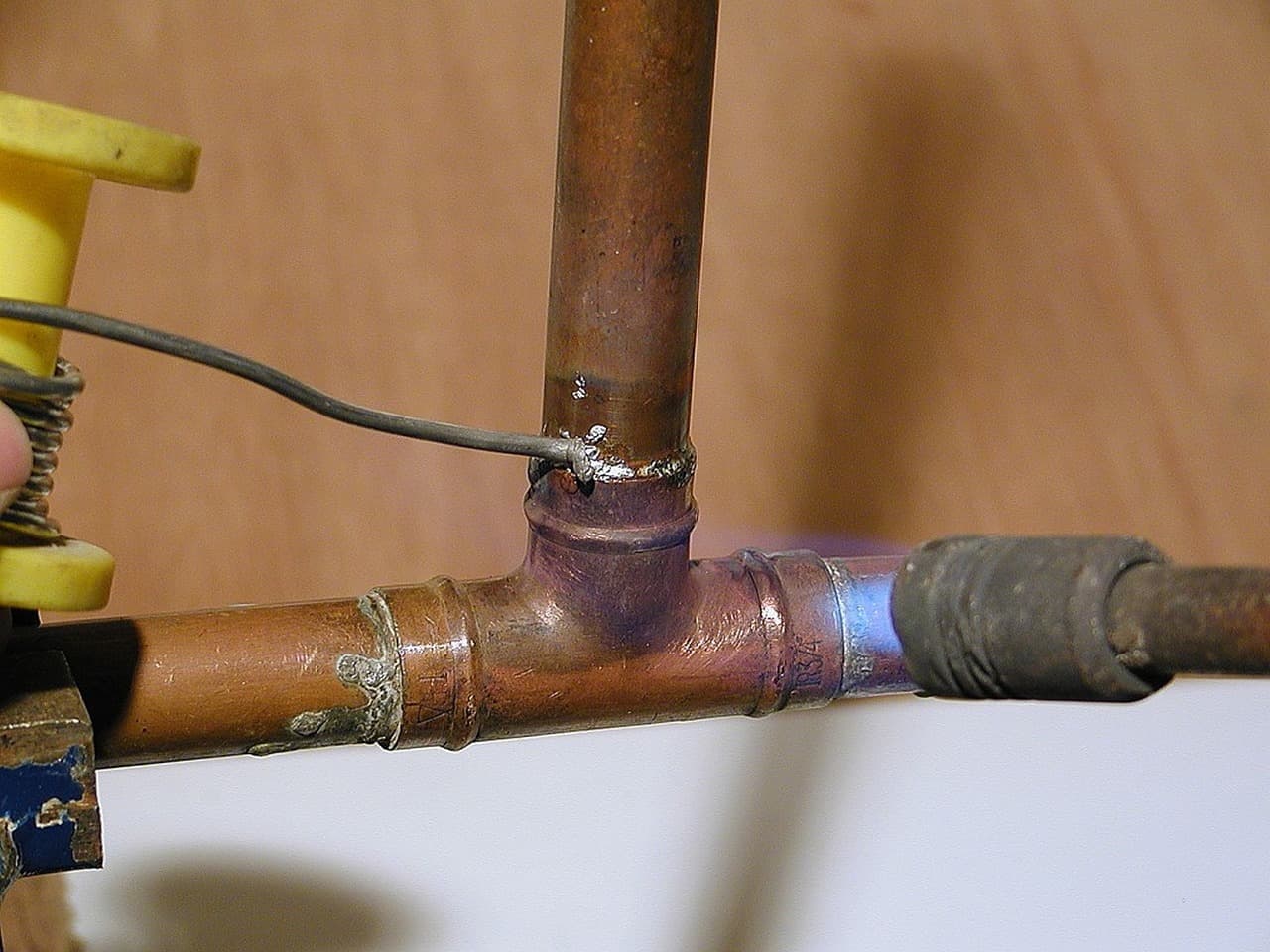 Copper pipe joints being soldered with a blowtorch