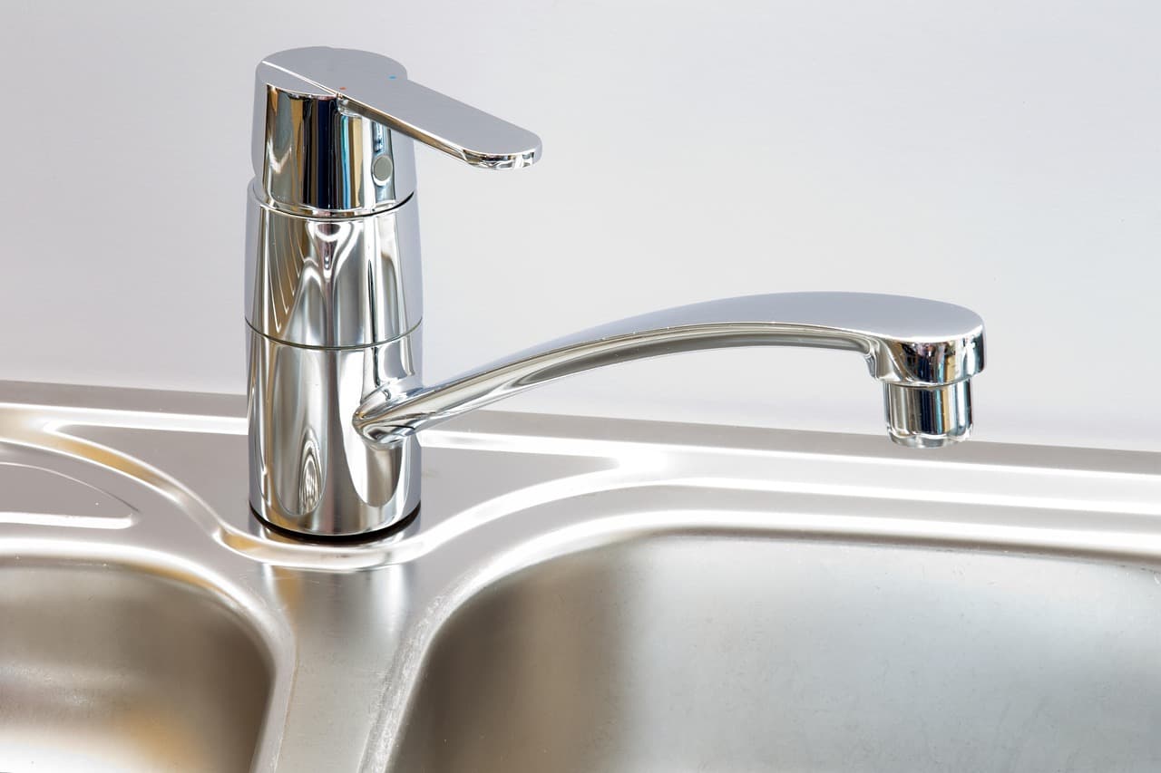 A chrome single-lever kitchen mixer tap over a stainless steel sink